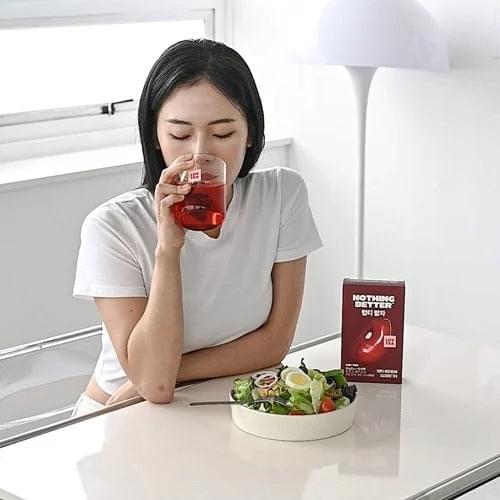 Woman sipping Luv Tea from a small cup with a cleanse tea box nearby