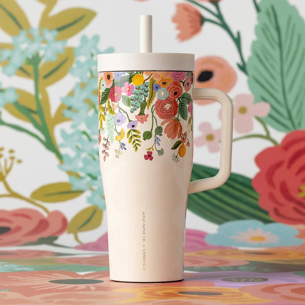 Cream insulated tumbler with floral pattern and straw lid, side handle visible.