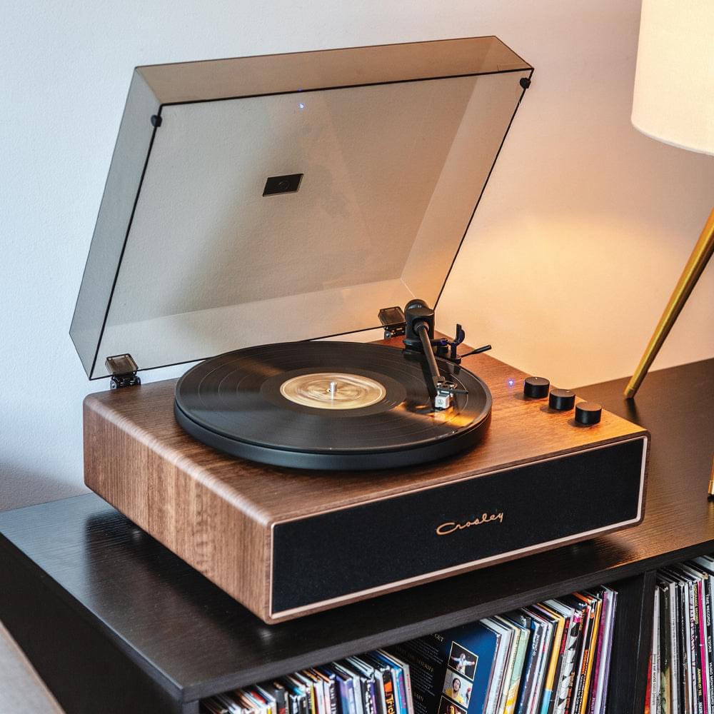 Walnut record player with open dust cover, vinyl on platter and tonearm controls