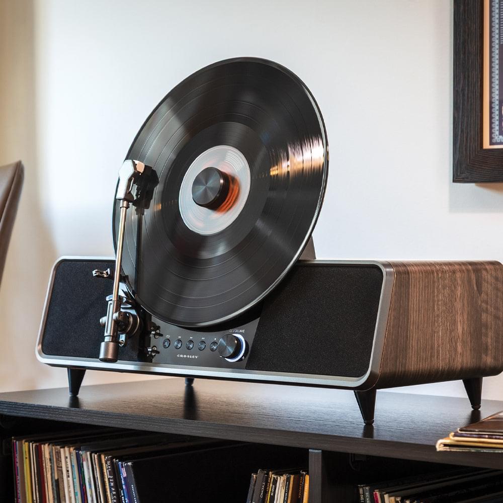 Crosley automatic vertical record player in walnut on shelf, black record spinning