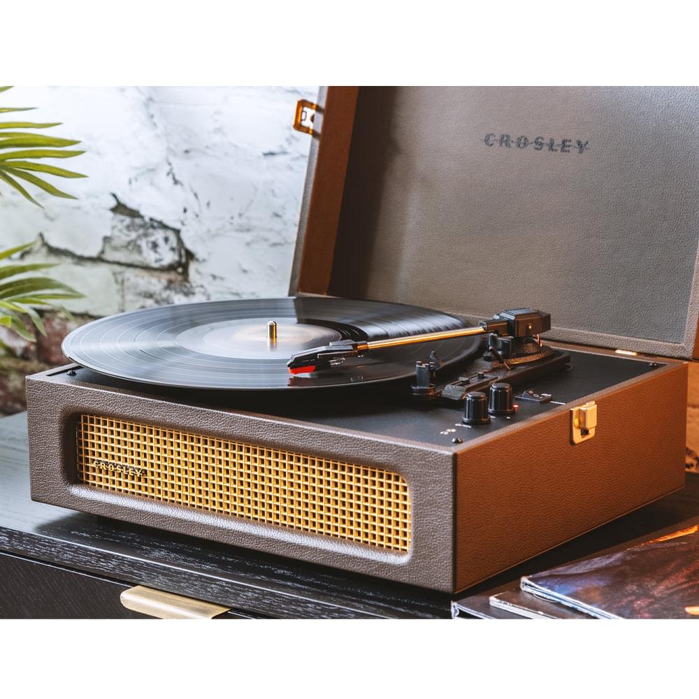 Crosley portable turntable playing a vinyl record with gold front speaker grille