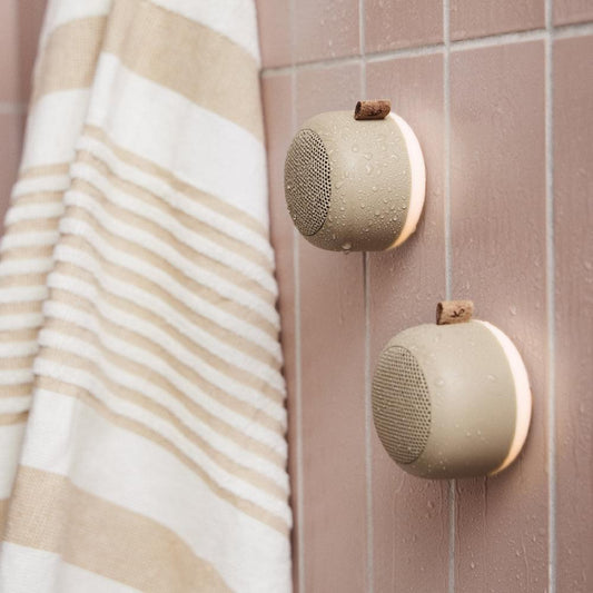 Pair of ivory sand Bluetooth speakers mounted on wall with fabric strap