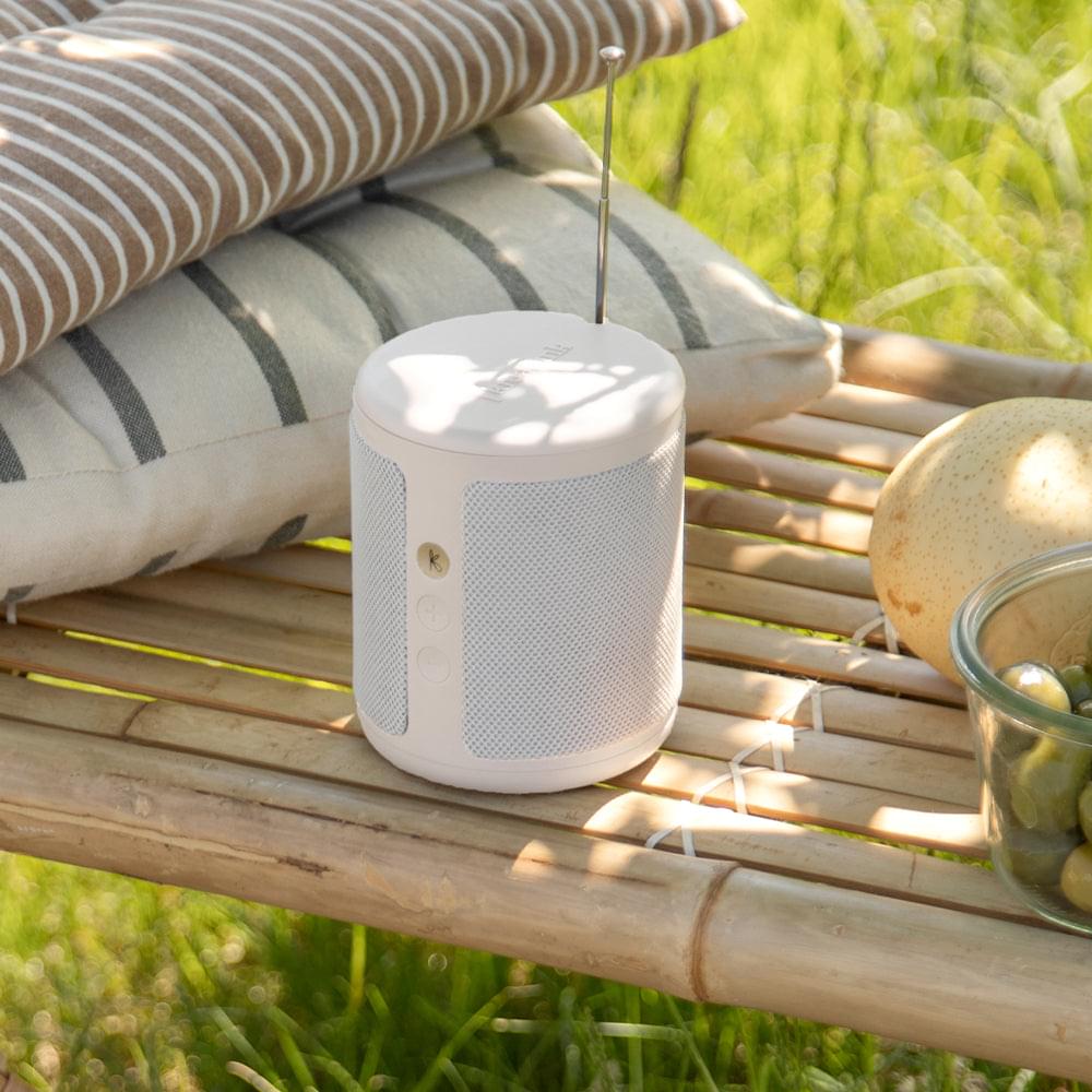 Kreafunk Dabbie soft white Bluetooth DAB+/FM radio speaker on a wooden bench outdoors