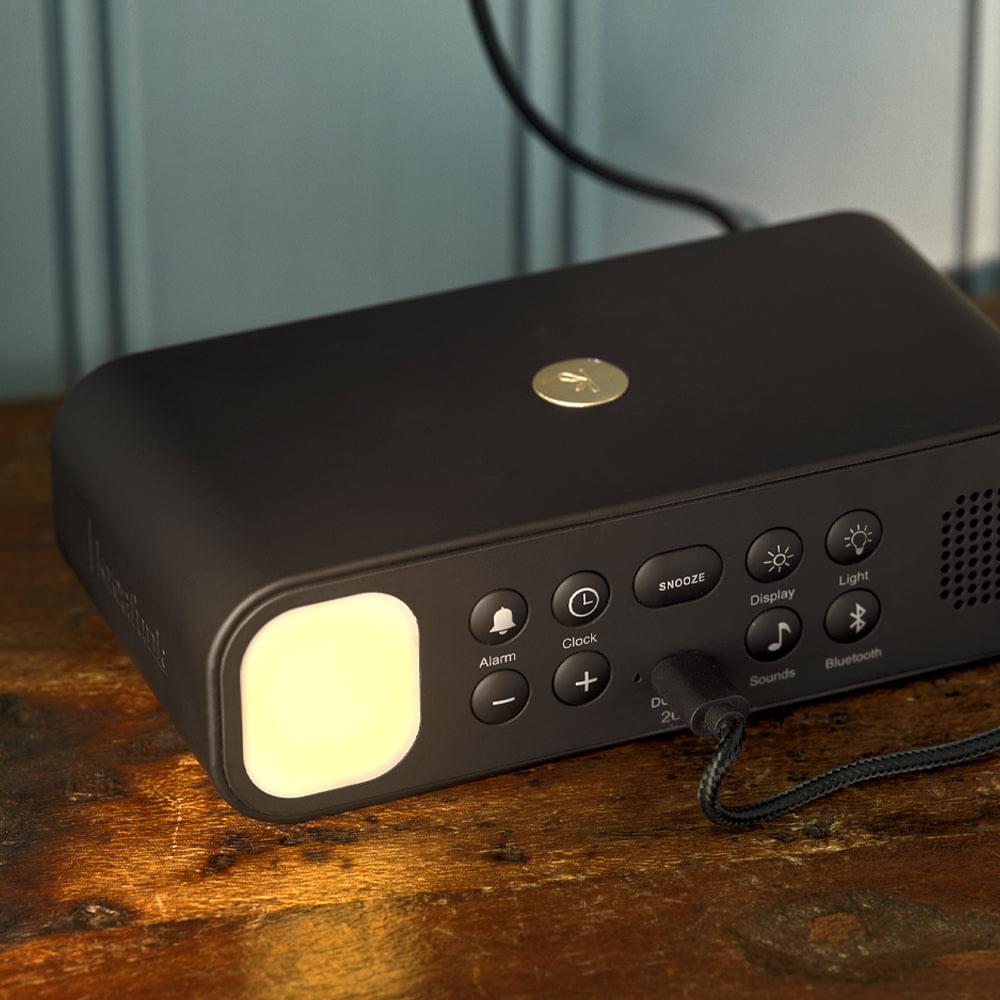 Green alarm clock speaker with front buttons and glowing light indicator