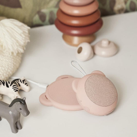 Dusty rose kids Bluetooth speaker with round grille and bear-ear shape, lying down