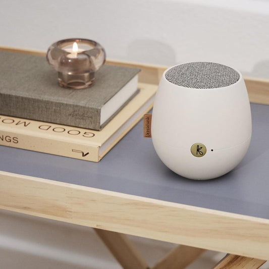 White Bluetooth speaker, side view with fabric speaker grille and K logo