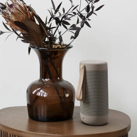 Compact ivory Bluetooth speaker standing with perforated front and side strap loop