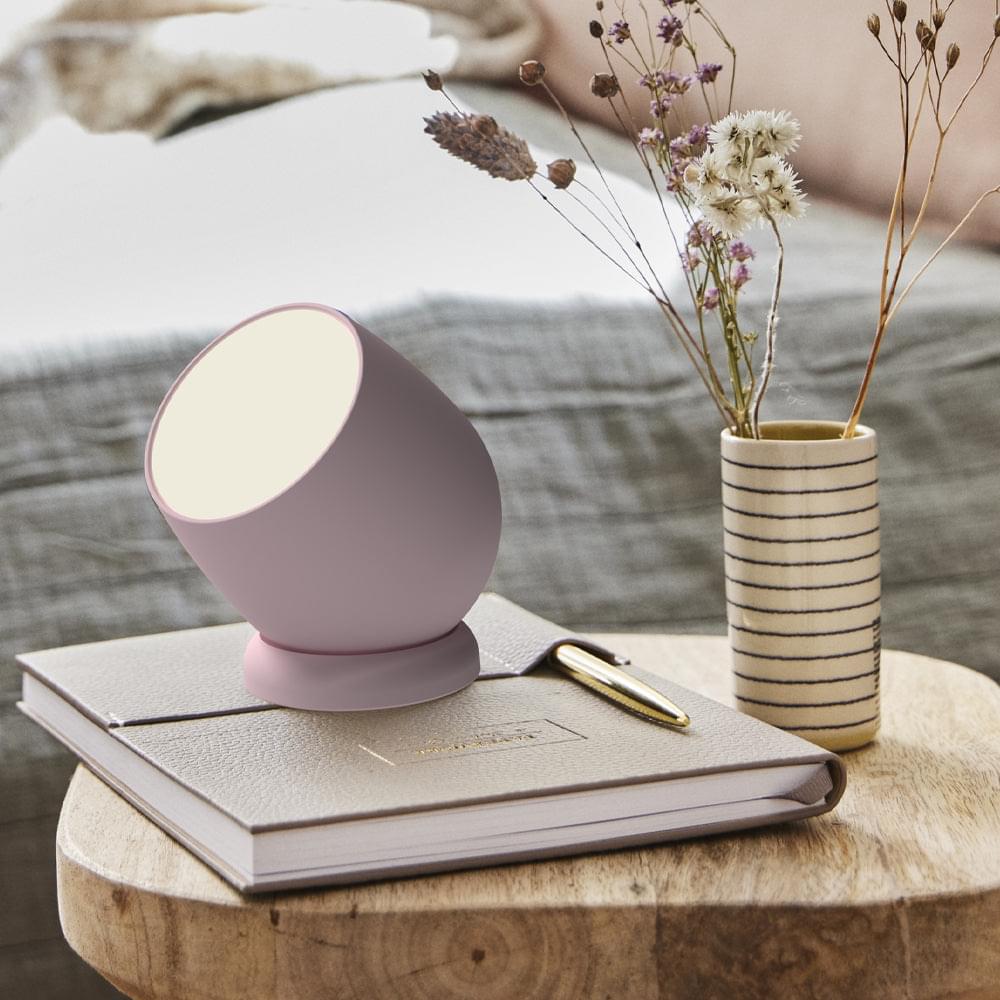 Dusty rose Kreafunk lamp with glowing round top and curved body, side view
