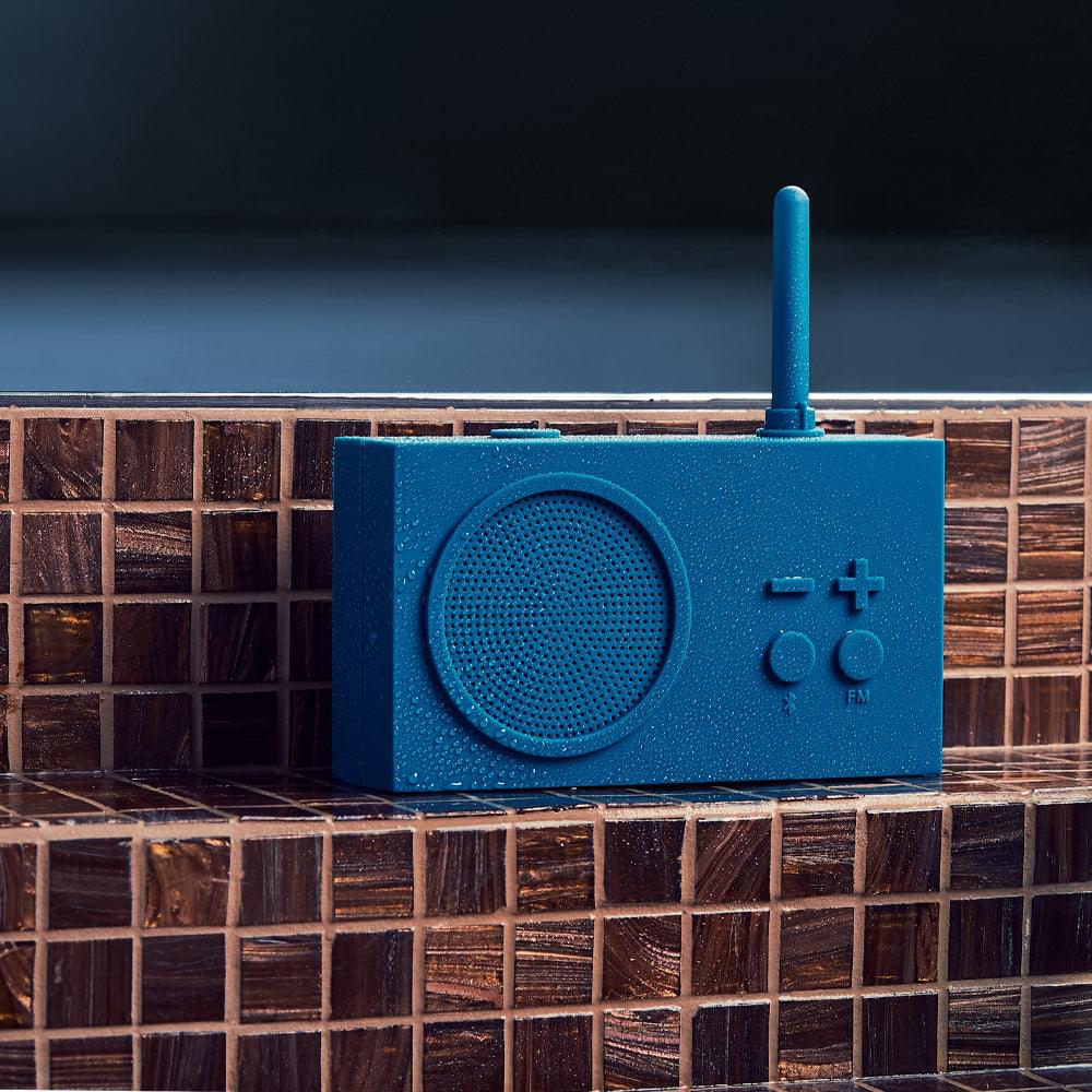 Blue portable radio speaker with circular grille, antenna, and FM tuning controls