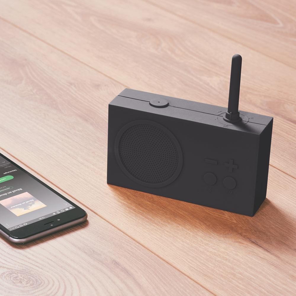 Black FM radio and Bluetooth speaker with antenna on a wooden surface