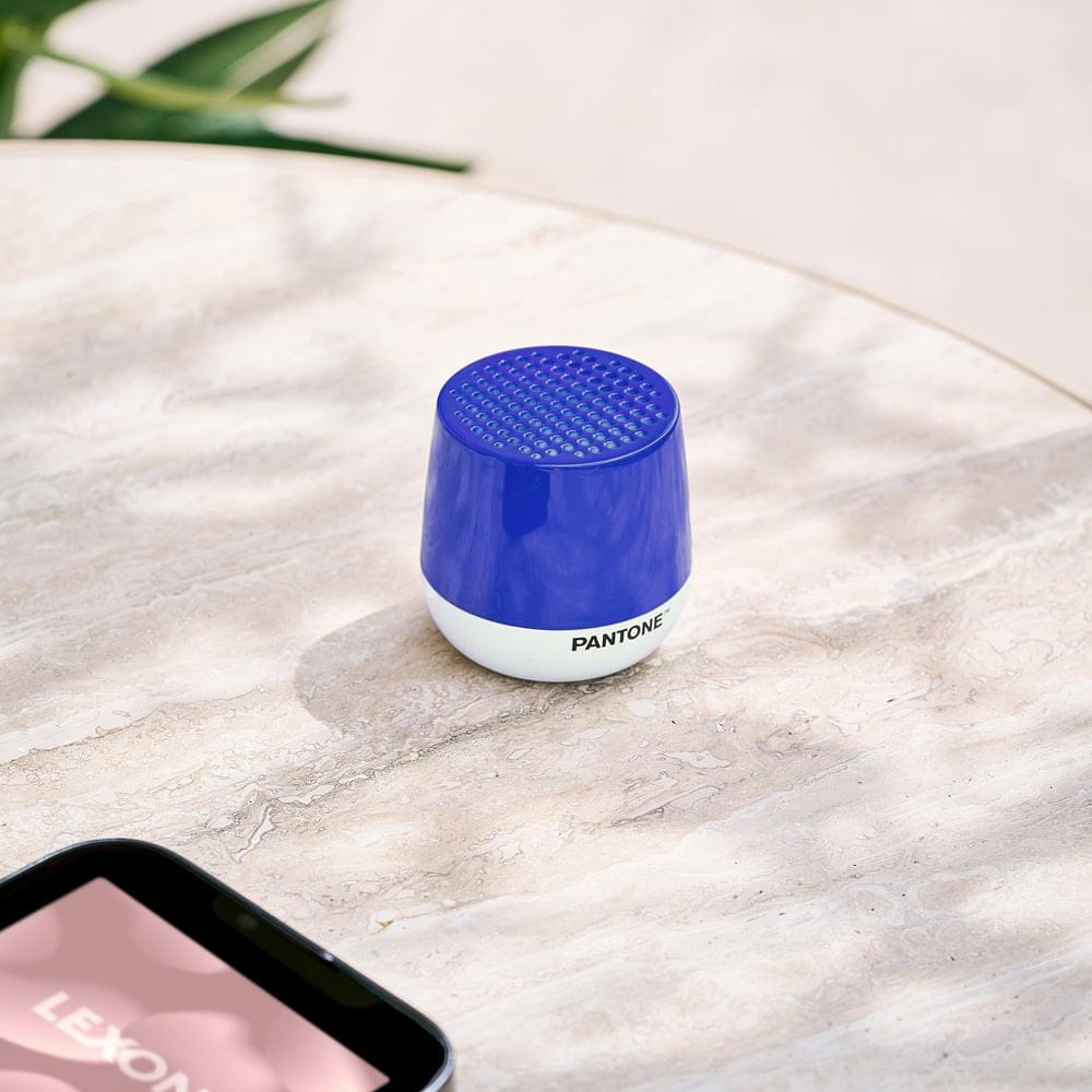 Mini Bluetooth speaker, blue grille top and white base, placed on light stone surface