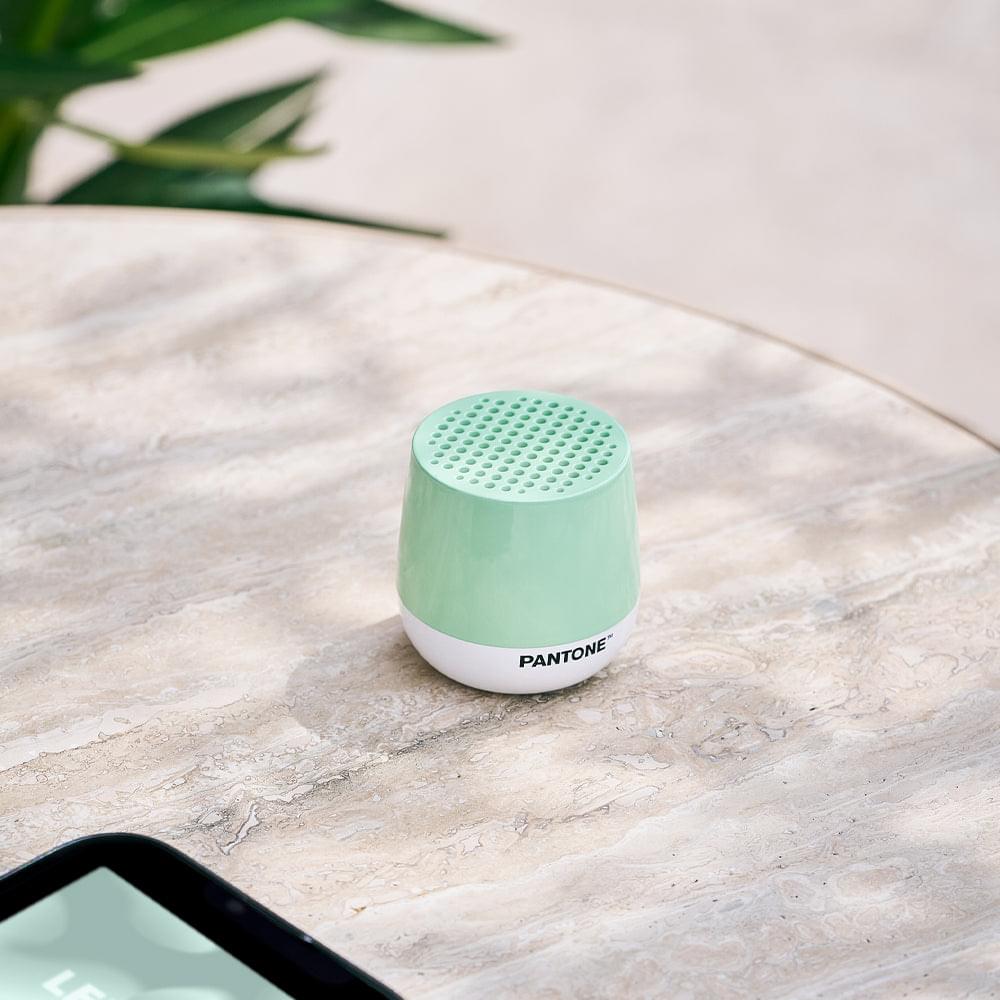 Mint green mini speaker with perforated top on a marble surface