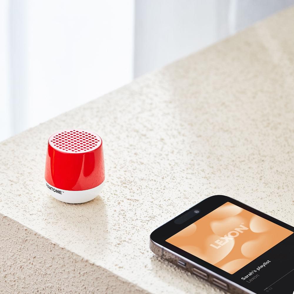Compact red Bluetooth speaker with perforated grille top and white bottom, PANTONE