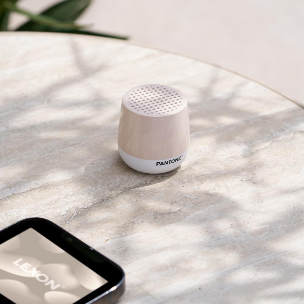 Sand mini Bluetooth speaker on circular surface, with top perforated grille