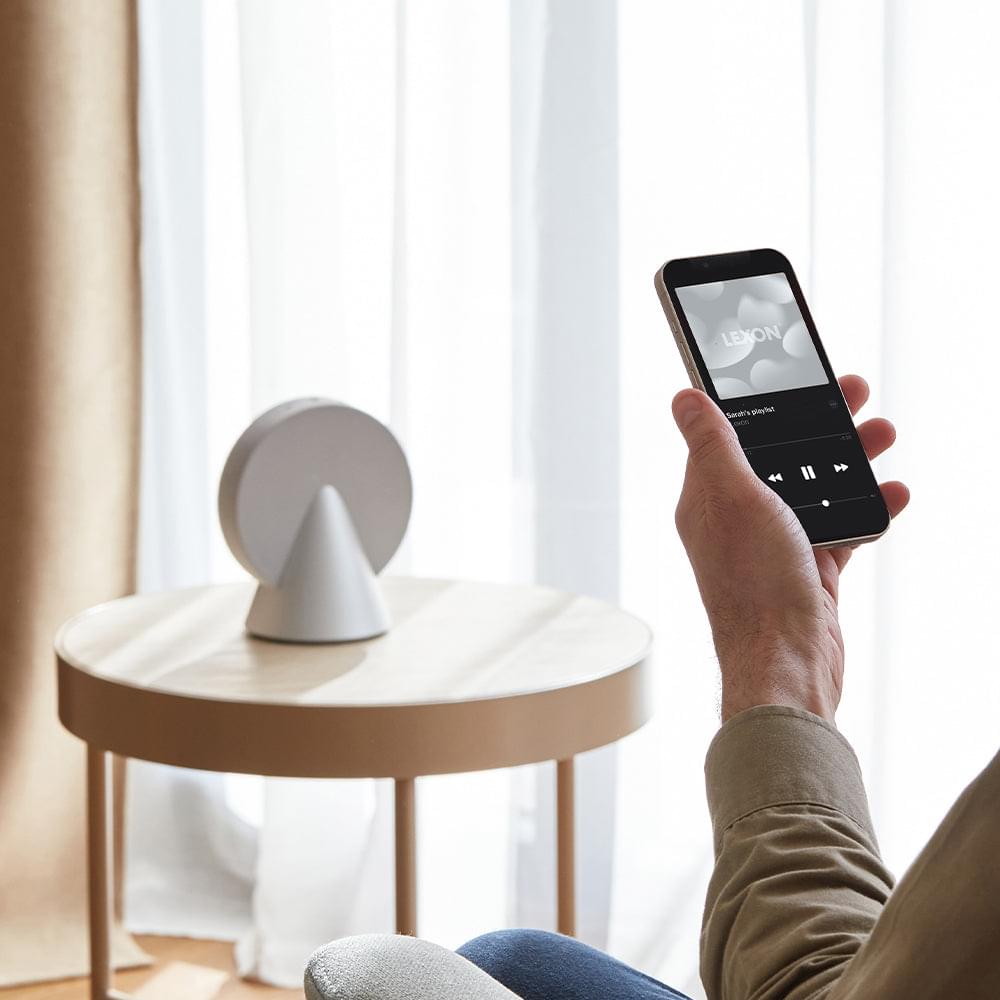 Lexon conic Bluetooth speaker with person using smartphone app controls
