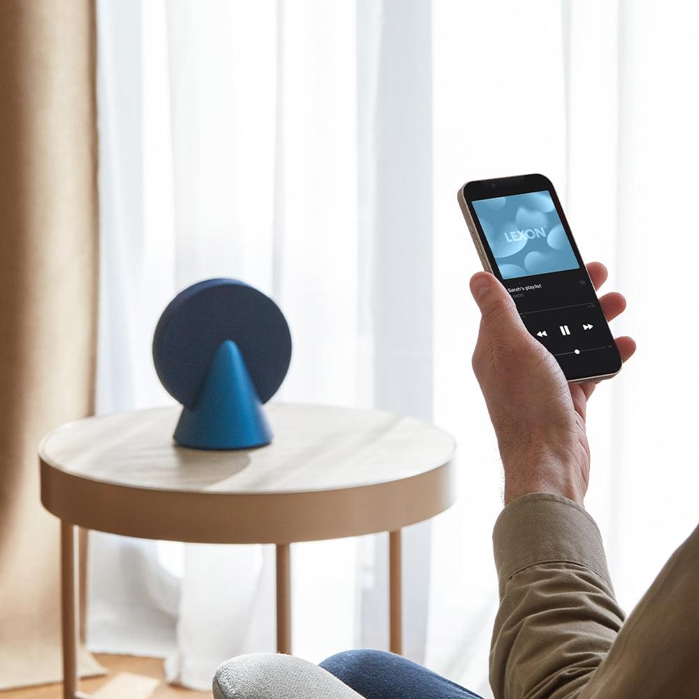 Blue conic Bluetooth speaker with fabric sound grille on a round tabletop
