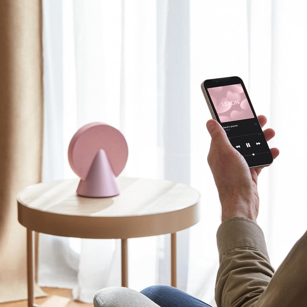 Pink conic Bluetooth speaker with silver base, controlled from a smartphone