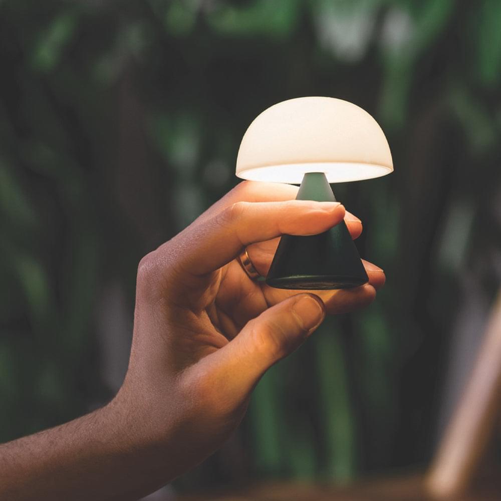 Mini LED lamp with green base and white dome shade, hand holding