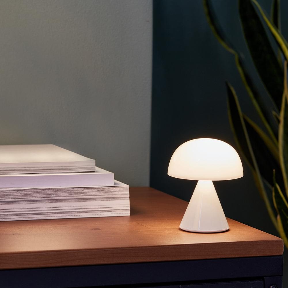 Lexon Mina mini LED lamp on shelf, white domed shade with warm light glow
