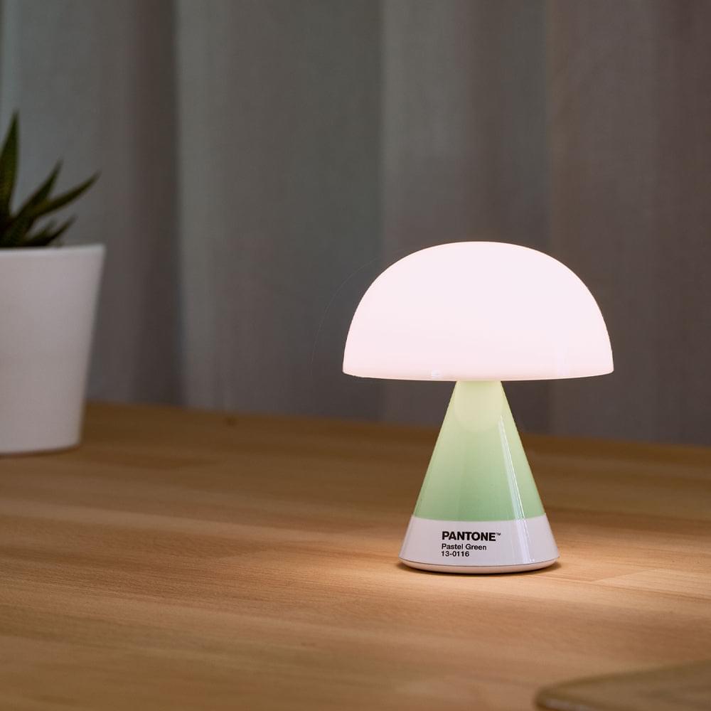 Green portable LED lamp with frosted white shade emitting soft warm glow; PANTONE label
