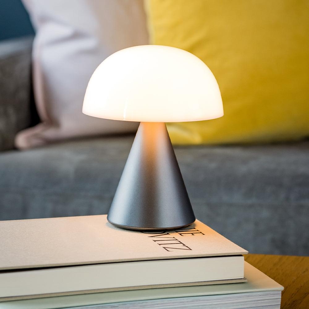 Portable LED lamp glowing warm light with white dome diffuser and gunmetal base