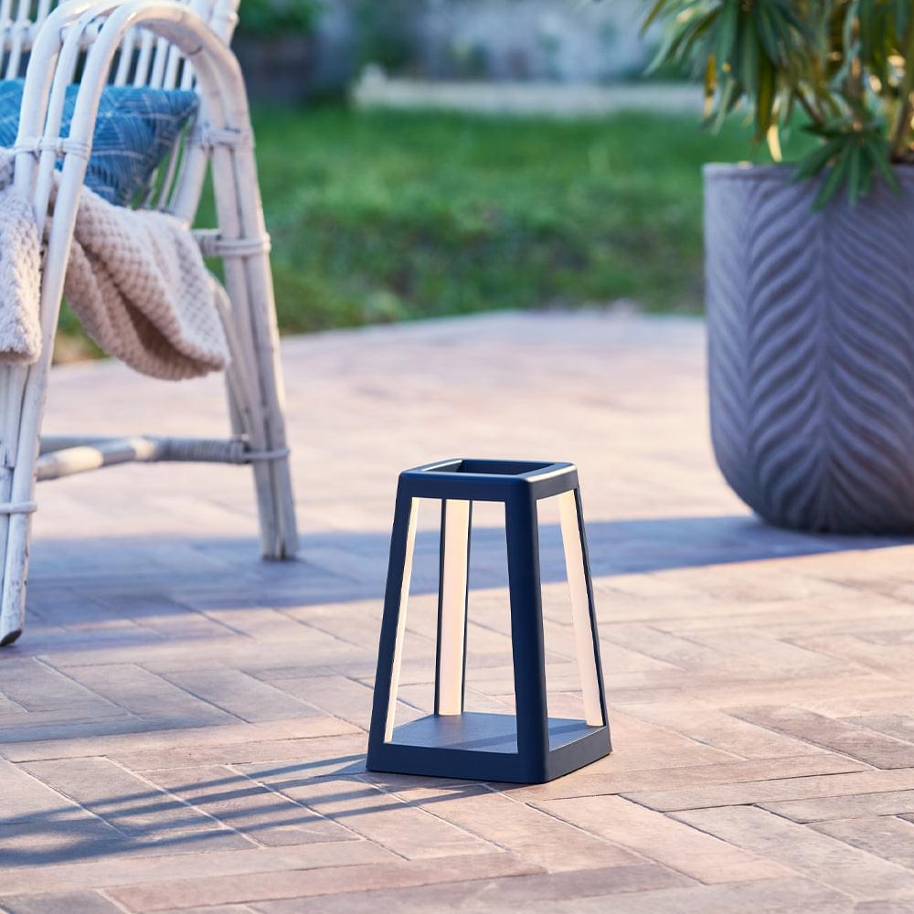 Blue portable lantern lamp on patio tile, open frame with glowing light tubes