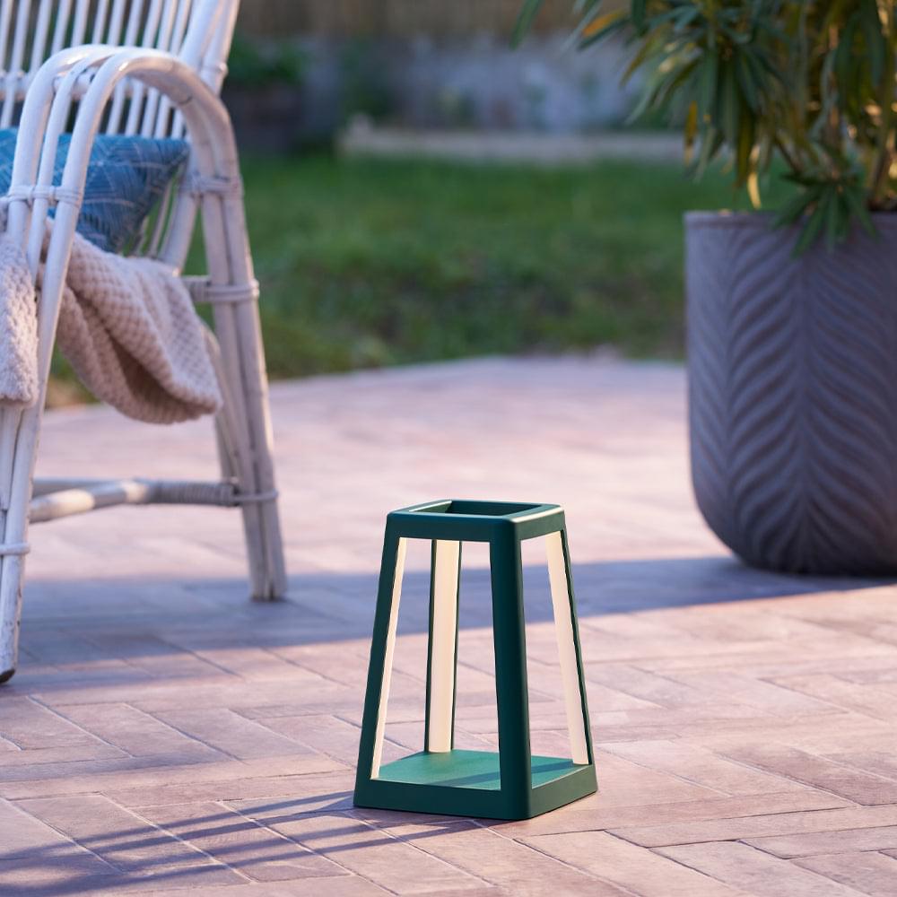 Green portable lantern lamp outdoors on patio tiles