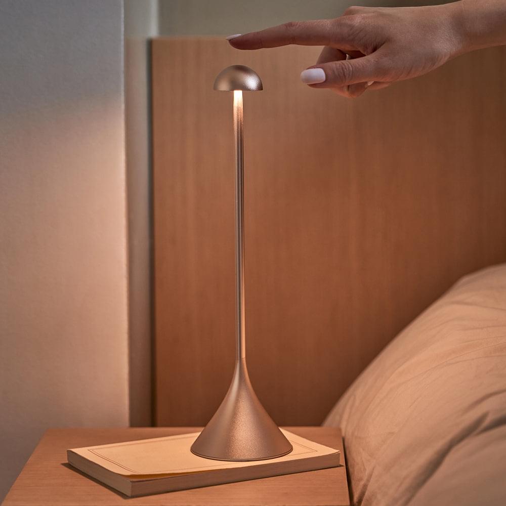 Gold dome-top table lamp on a bedside surface with flared base.