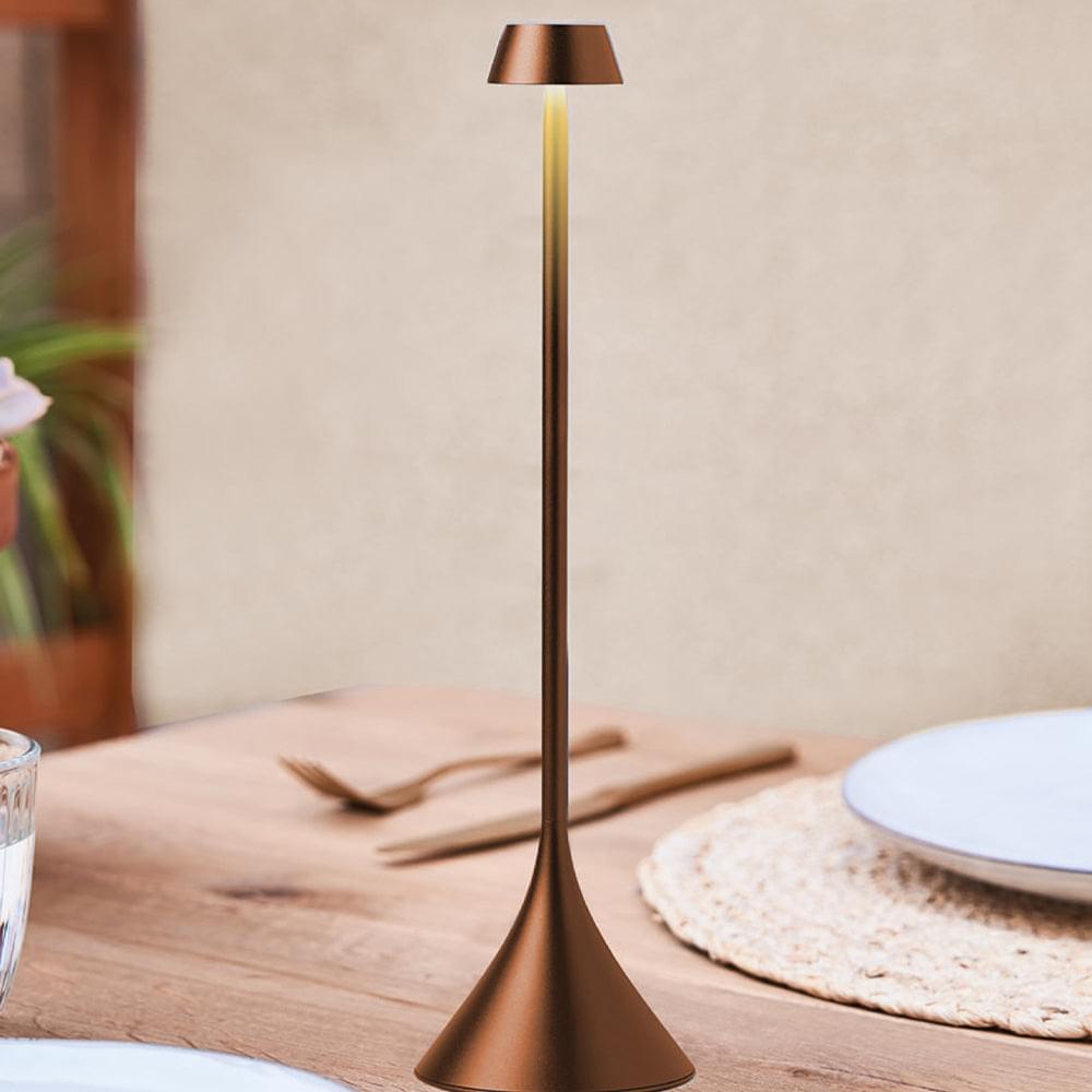 Bronze table lamp with conical shade and tapered flared base, on wooden table