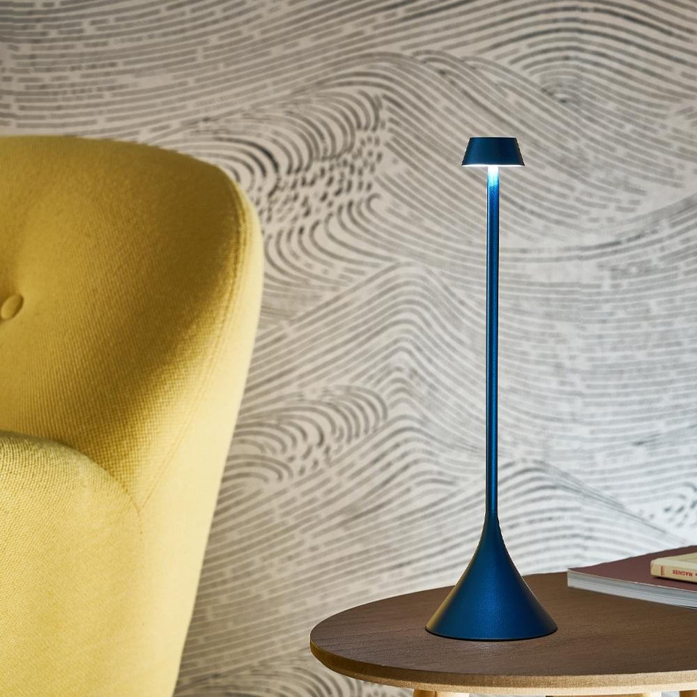 Blue conical-shade table lamp on a side surface beside an upholstered chair