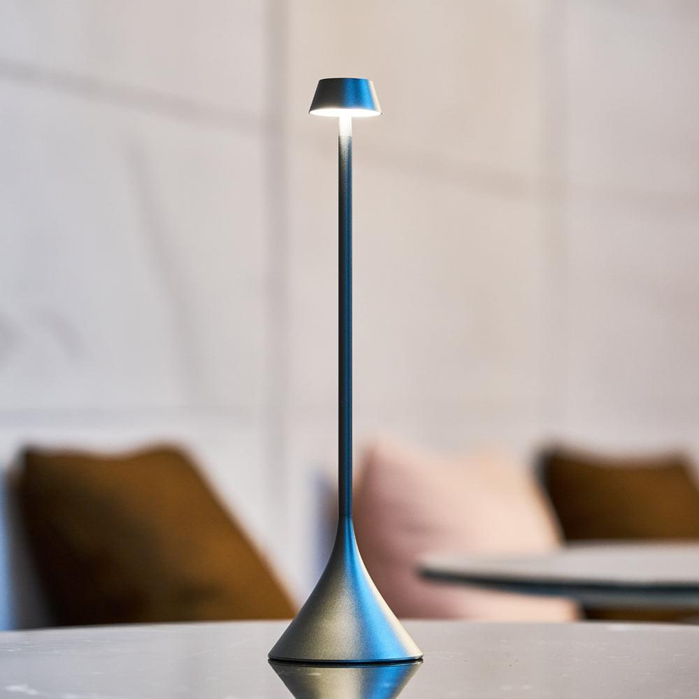 Gunmetal table lamp with conical shade, lit with blue glow near base
