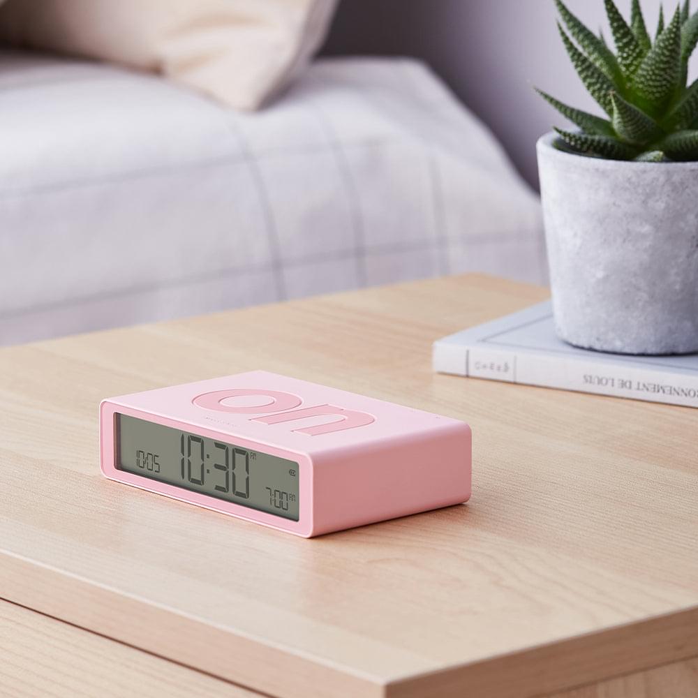 Pink flip reversible alarm clock on table with front digital display showing time