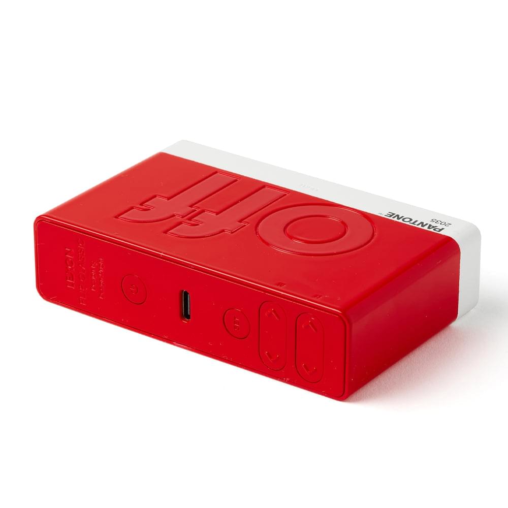 Red flip alarm clock with side buttons and ports, angled side view
