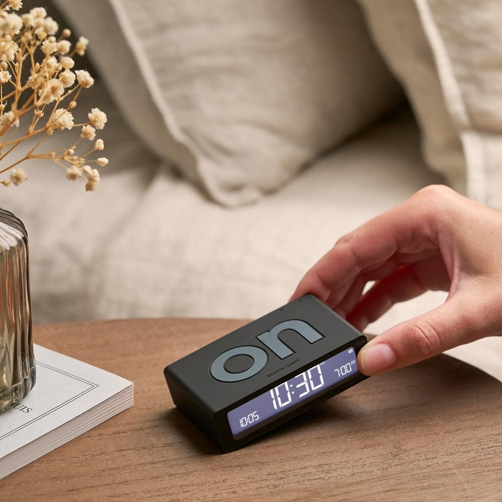 Black reversible flip mini alarm clock on desk, blue digits visible during flipping
