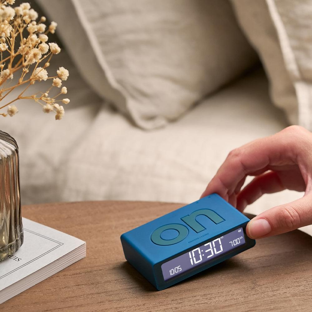 Blue Lexon flip mini reversible alarm clock, hand holding front display with time
