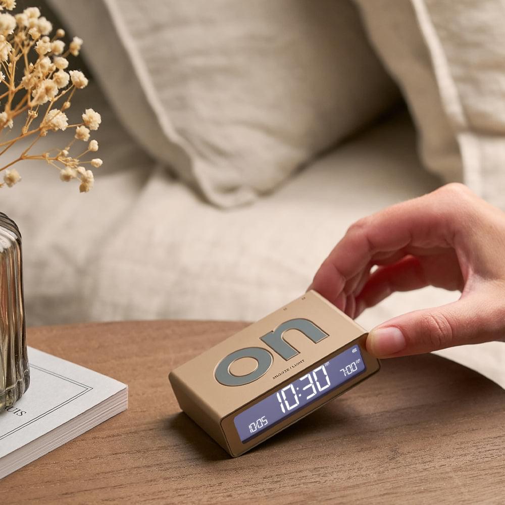 Gold Lexon flip mini reversible alarm clock held in hand, showing digital display