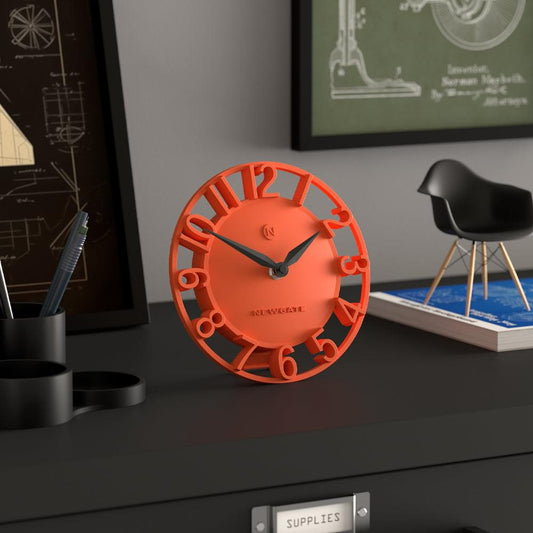 Orange Newgate mantel clock on desk, open frame Roman numerals and black hands