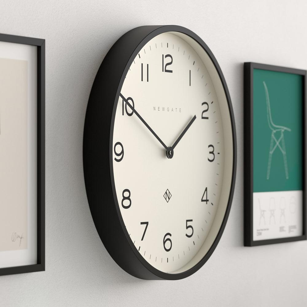 Black wall clock with cream dial, black hands, and Arabic numerals on thick rim