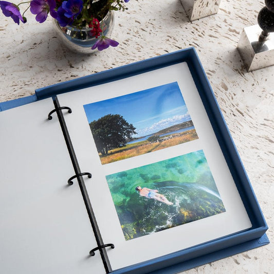 Blue photo album open with black rings and two landscape photo pages