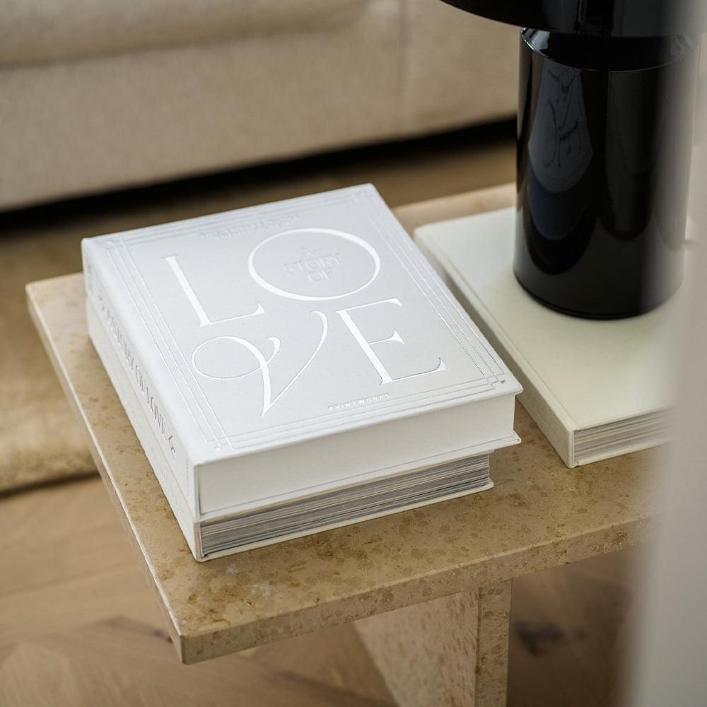 Stack of white wedding photo albums with embossed “LOVE” and “A STORY” circle