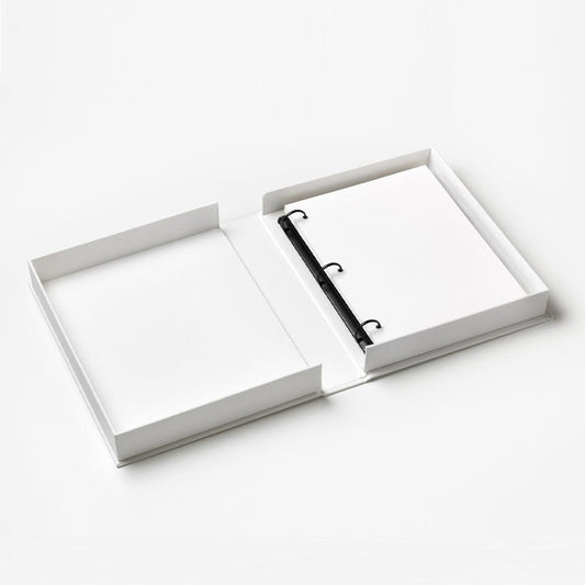 Open baby photo album with white pages and black ring binder