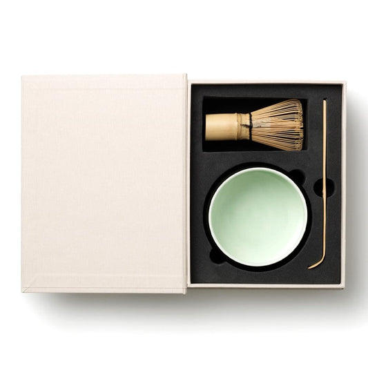 Matcha tools set in beige box: green bowl, bamboo whisk, and whisking scoop