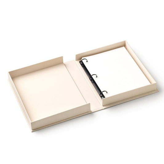 Photo album opened with beige pages and black binder rings in the center