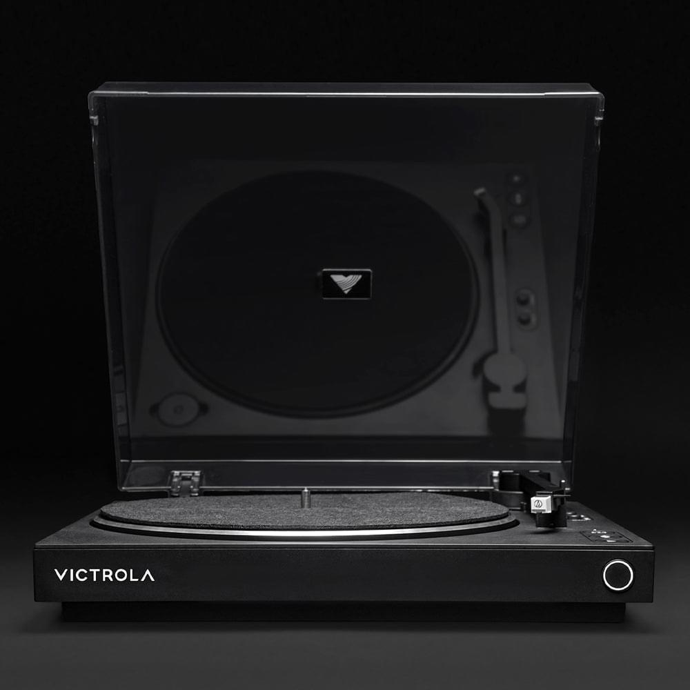 Black turntable with closed dust cover and vinyl record on platter