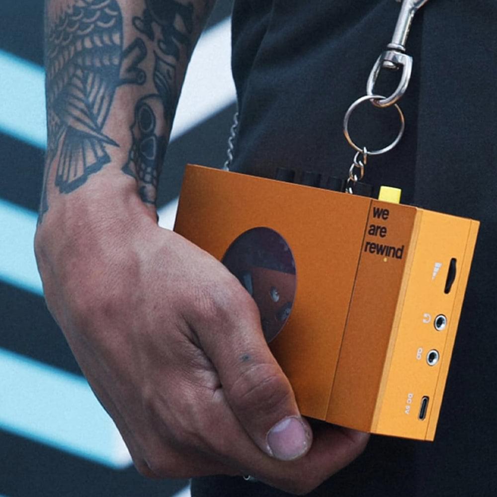 Orange portable cassette player & recorder in hand with front panel and controls visible