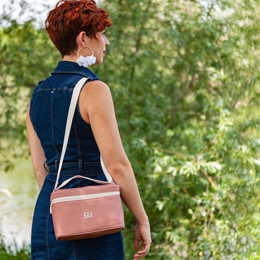 Insulated lunch cooler bag carried crossbody, pink with light trim and Monbento logo.