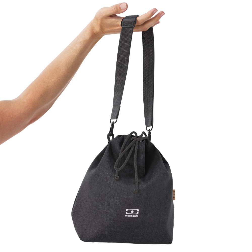 Insulated lunch bag worn crossbody with drawstring top, black fabric and Monbento logo.