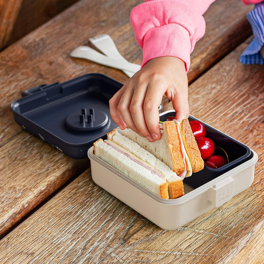 Open blue-and-white lunch box packed with sandwiches and cherry tomatoes on table