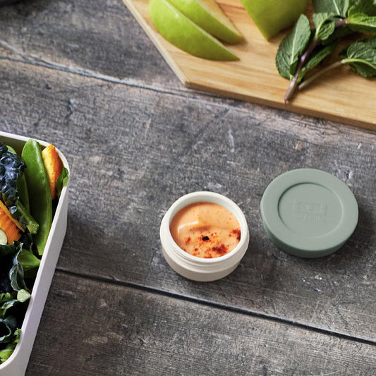 Monbento sauce cup with dip, green lid beside