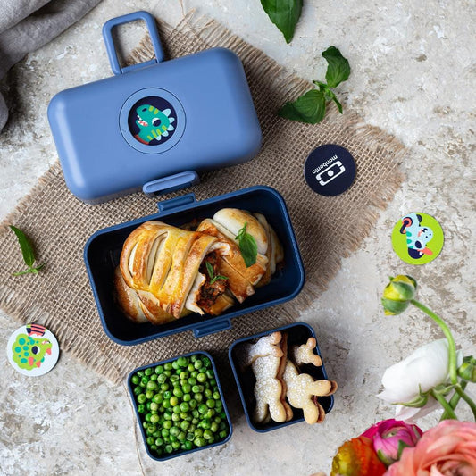 Blue kids bento box open with divided compartments holding vegetables and chicken